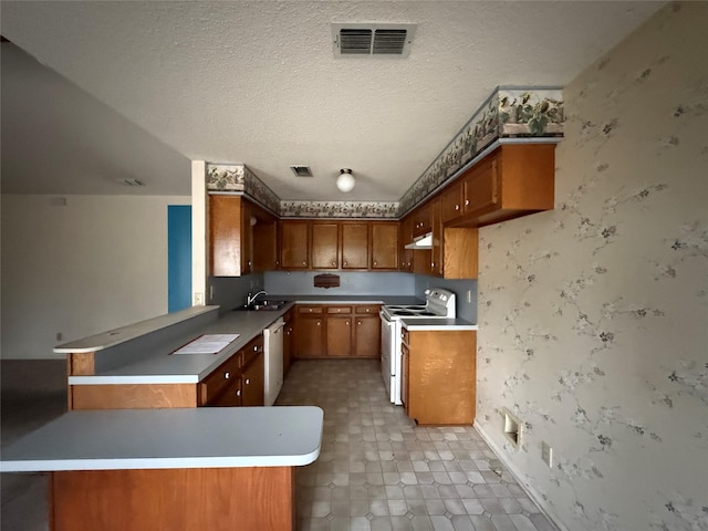 kitchen with white appliances, visible vents, a peninsula, a textured ceiling, and a sink