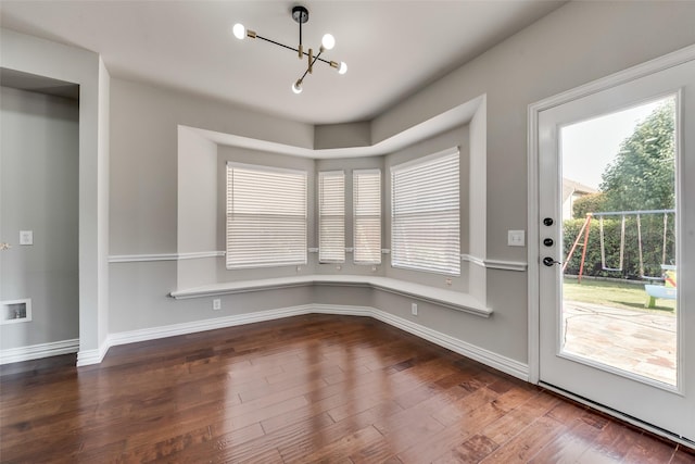 unfurnished dining area with a chandelier, baseboards, and wood finished floors