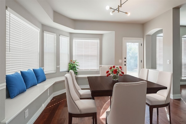 dining space featuring a chandelier, arched walkways, and dark wood-style flooring