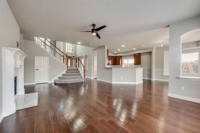 unfurnished living room with dark wood-type flooring, visible vents, a high end fireplace, baseboards, and stairway