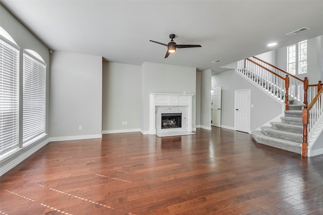 unfurnished living room featuring visible vents, a premium fireplace, stairway, and hardwood / wood-style floors