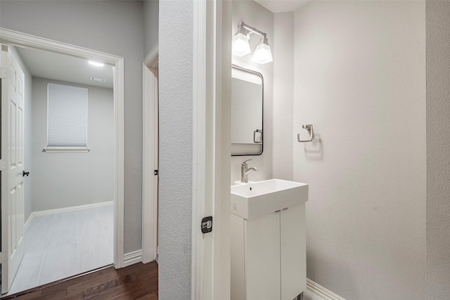 bathroom with wood finished floors, vanity, and baseboards