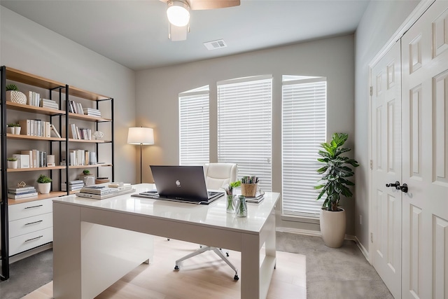 office featuring visible vents, ceiling fan, light carpet, and baseboards