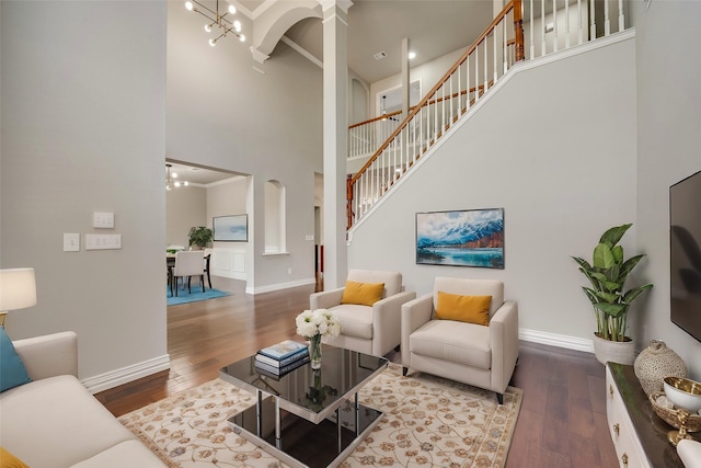 living room featuring wood finished floors, a high ceiling, baseboards, and an inviting chandelier