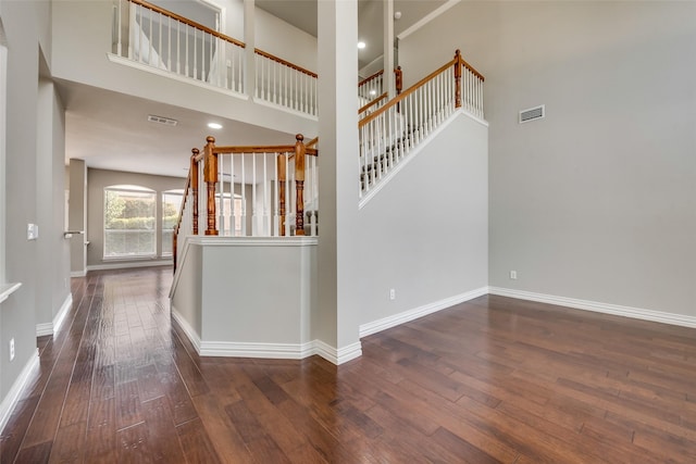 stairs featuring a high ceiling, wood-type flooring, visible vents, and baseboards