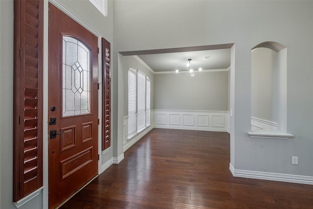 entrance foyer with wood-type flooring, ornamental molding, a decorative wall, and wainscoting