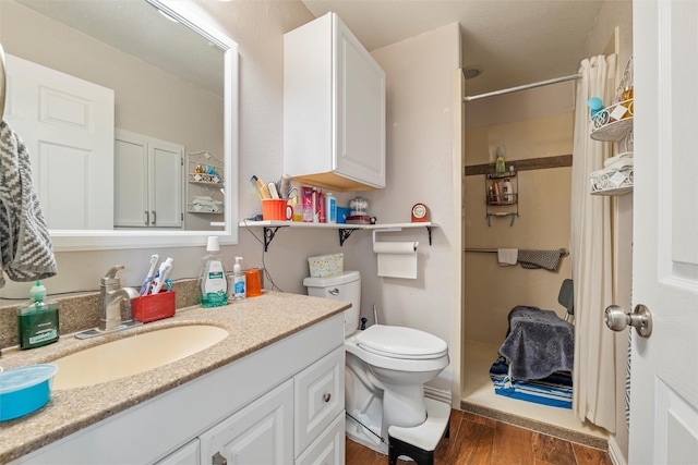 bathroom featuring a shower, vanity, wood finished floors, and toilet