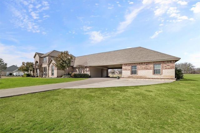 view of front facade featuring a shingled roof, a front yard, brick siding, and driveway