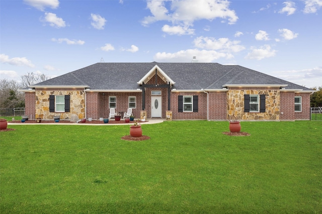 view of front of property featuring stone siding, a front lawn, and roof with shingles