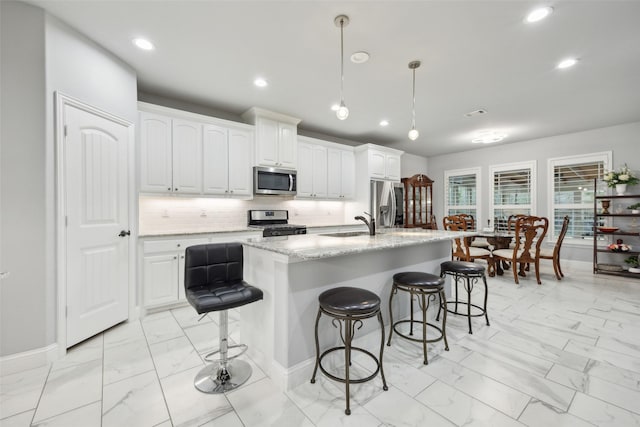 kitchen with stainless steel appliances, a breakfast bar, marble finish floor, and white cabinets