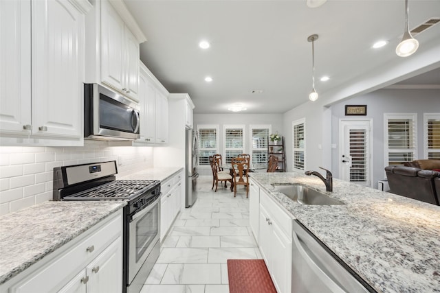 kitchen featuring stainless steel appliances, a sink, white cabinets, marble finish floor, and backsplash