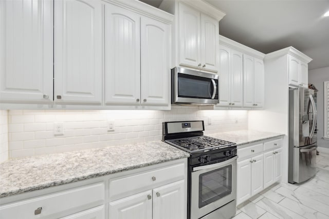 kitchen featuring light stone counters, marble finish floor, tasteful backsplash, appliances with stainless steel finishes, and white cabinets