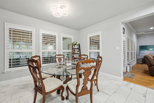 dining area with marble finish floor, crown molding, and baseboards