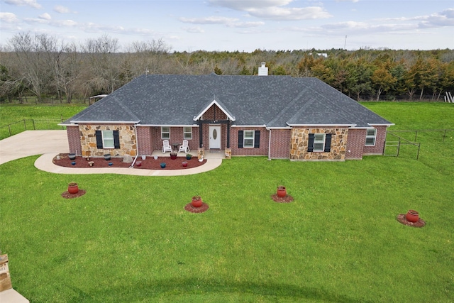 view of front of house featuring a chimney, a shingled roof, a front yard, fence, and stone siding