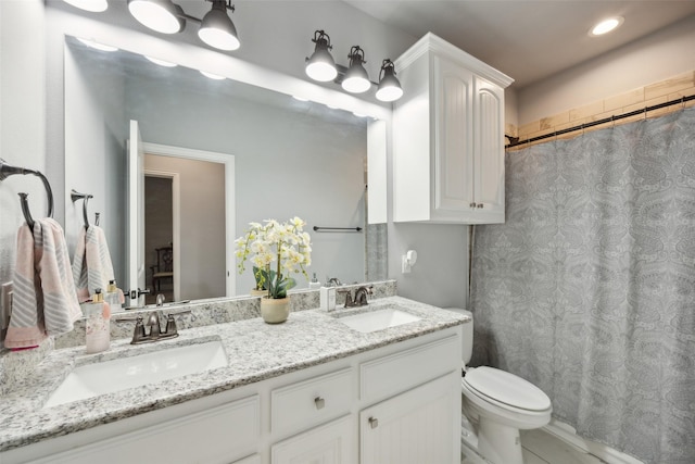 bathroom featuring double vanity, toilet, a sink, and recessed lighting