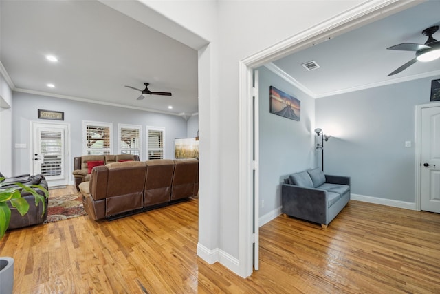 living area with ornamental molding, ceiling fan, light wood-style flooring, and visible vents