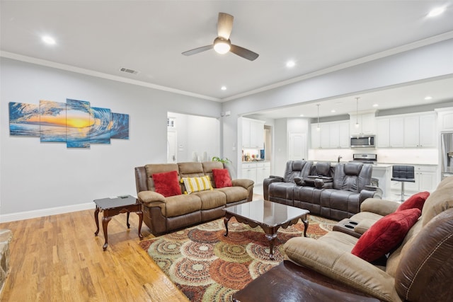 living area featuring visible vents, baseboards, light wood-style flooring, ornamental molding, and recessed lighting