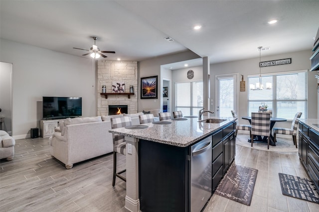 kitchen with dark cabinets, wood tiled floor, open floor plan, and a sink