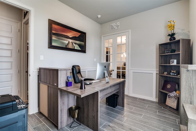 office with wood tiled floor, french doors, a wainscoted wall, and a decorative wall