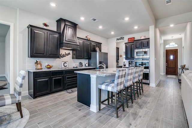 kitchen featuring premium range hood, appliances with stainless steel finishes, wood finish floors, and visible vents