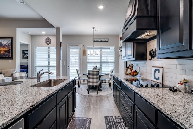 kitchen with dark cabinets, a sink, custom exhaust hood, and black electric cooktop