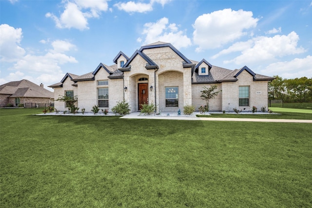 french country inspired facade with roof with shingles, a front lawn, and brick siding