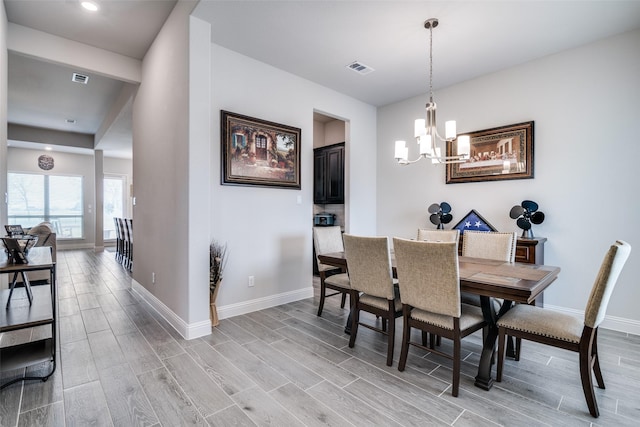 dining room featuring an inviting chandelier, wood tiled floor, visible vents, and baseboards