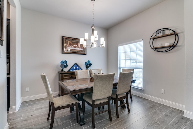 dining room with baseboards, a chandelier, and wood finish floors