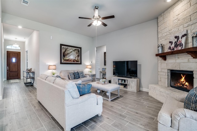 living room featuring visible vents, baseboards, ceiling fan, wood finish floors, and a fireplace