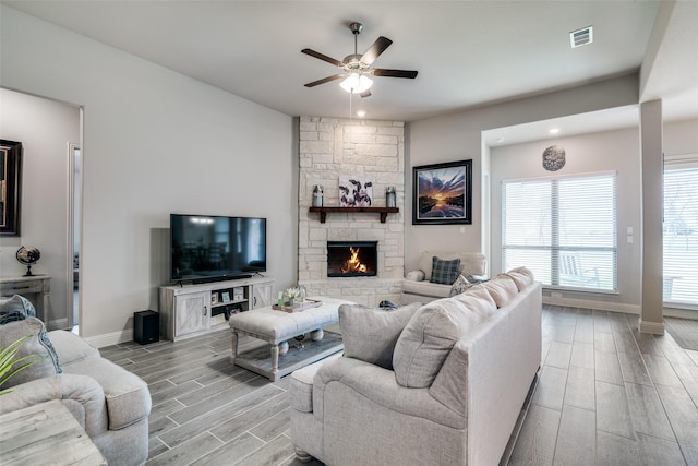 living area featuring baseboards, visible vents, ceiling fan, wood finish floors, and a fireplace