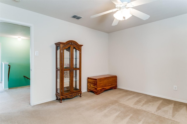 carpeted spare room with baseboards, visible vents, and a ceiling fan