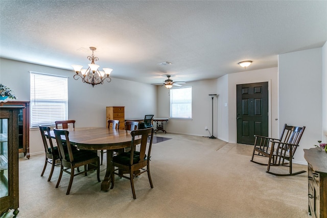 dining space featuring light carpet, a textured ceiling, ceiling fan with notable chandelier, and baseboards