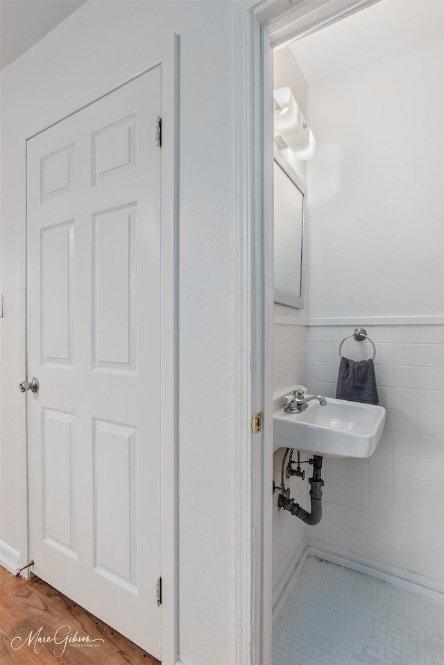 bathroom featuring a wainscoted wall, a sink, and tile walls