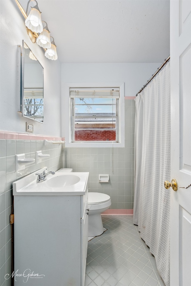 full bathroom with tile walls, toilet, wainscoting, vanity, and tile patterned flooring