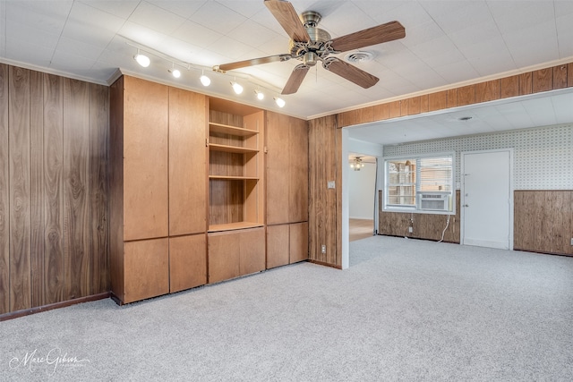 interior space featuring cooling unit, wood walls, carpet flooring, a ceiling fan, and ornamental molding