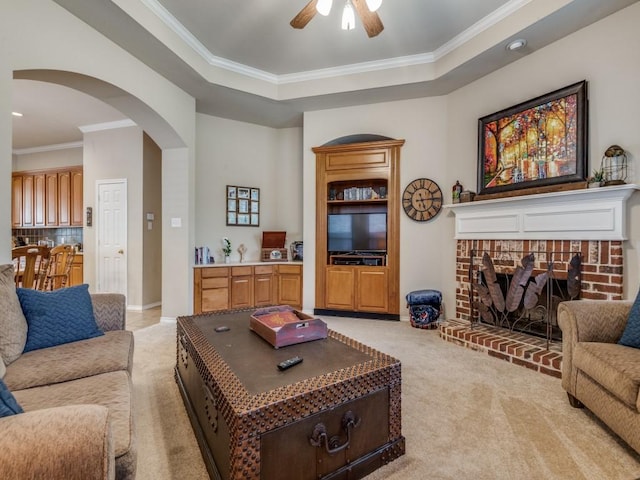 living area with arched walkways, a tray ceiling, crown molding, and light colored carpet