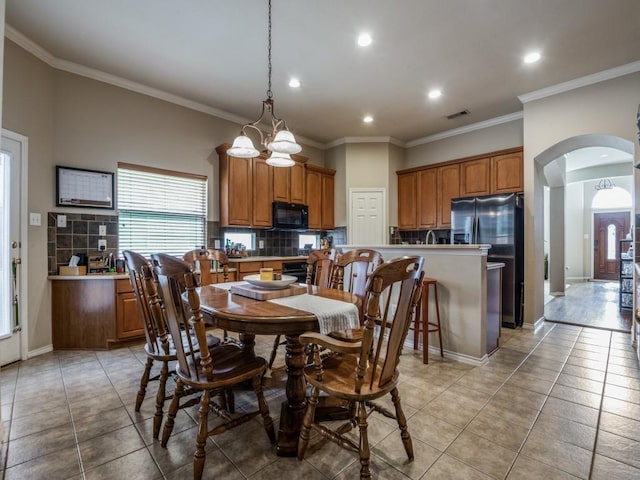 dining space with arched walkways, ornamental molding, light tile patterned floors, and baseboards