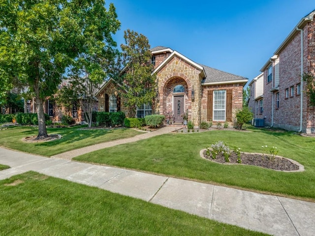 view of front of house with a front yard, stone siding, brick siding, and central air condition unit