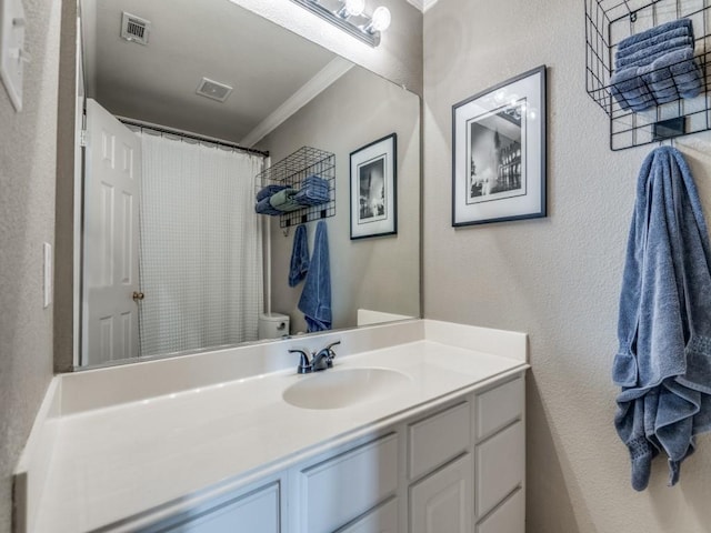 bathroom featuring toilet, vanity, visible vents, and crown molding