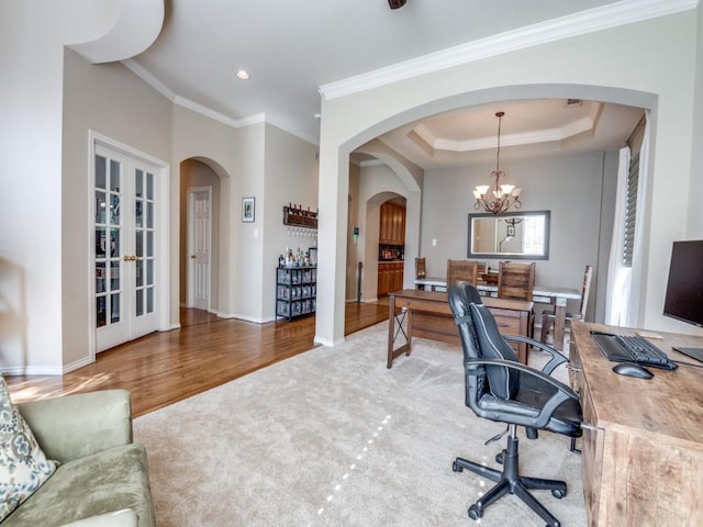 carpeted office space with a chandelier, ornamental molding, baseboards, and wood finished floors