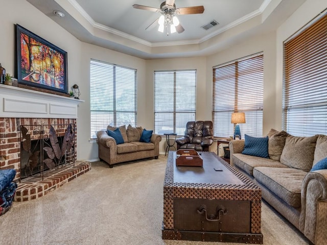 living room featuring visible vents, a ceiling fan, light colored carpet, a tray ceiling, and crown molding