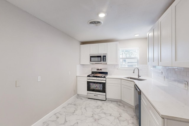 kitchen with marble finish floor, stainless steel appliances, tasteful backsplash, visible vents, and a sink