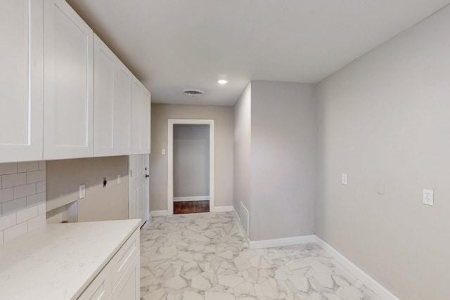 interior space with marble finish floor, visible vents, cabinet space, and baseboards