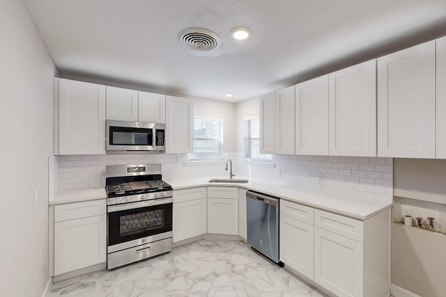 kitchen featuring a sink, visible vents, white cabinets, marble finish floor, and appliances with stainless steel finishes