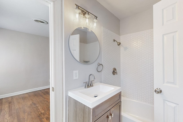 bathroom with bathing tub / shower combination, visible vents, vanity, wood finished floors, and baseboards