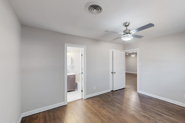 unfurnished bedroom with ensuite bathroom, ceiling fan, wood finished floors, visible vents, and baseboards