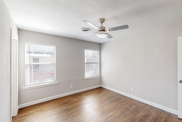 empty room featuring a ceiling fan, visible vents, baseboards, and wood finished floors