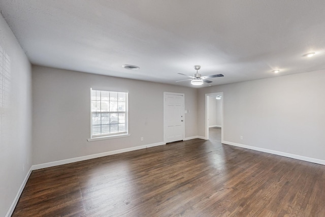 empty room featuring dark wood-type flooring, visible vents, and baseboards