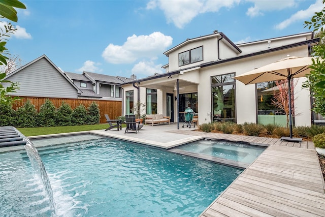 rear view of house featuring an in ground hot tub, a patio area, fence, and a fenced in pool