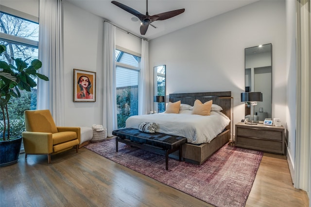 bedroom featuring a ceiling fan, multiple windows, and wood finished floors